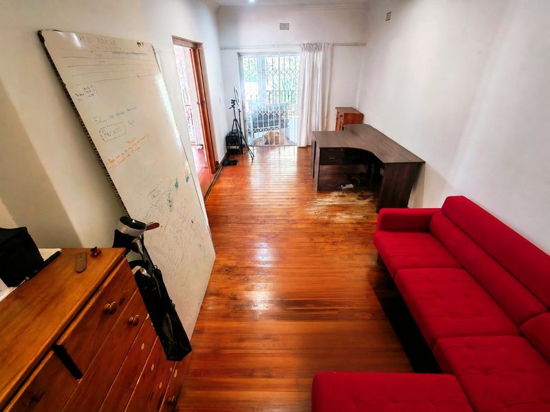 Living area featuring original hardwood flooring and access to an outdoor space through a security gate.