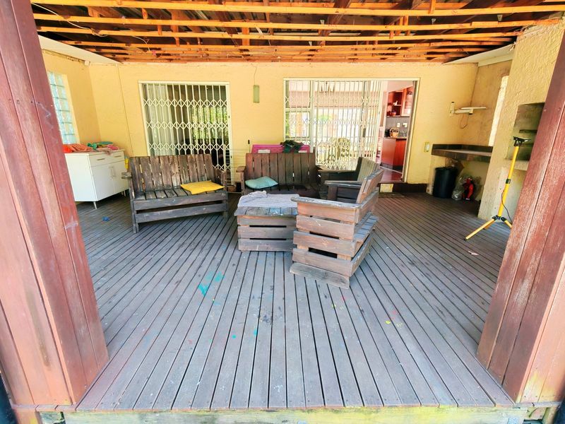 Covered outdoor patio featuring timber decking, a built-in braai, and exposed roof rafters, providing a functional space for outdoor entertainment.