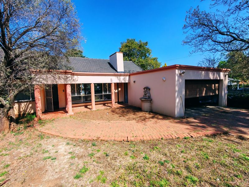 Front elevation of a single-story house featuring a paved driveway, attached garage, covered patio with columns, and a tiled roof.