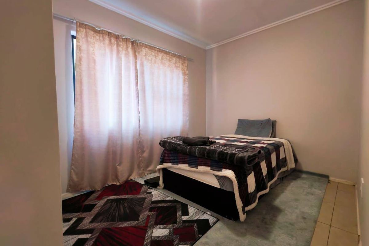 A standard bedroom featuring tiled flooring and neutral wall finishes, providing a functional space with natural light from the window.