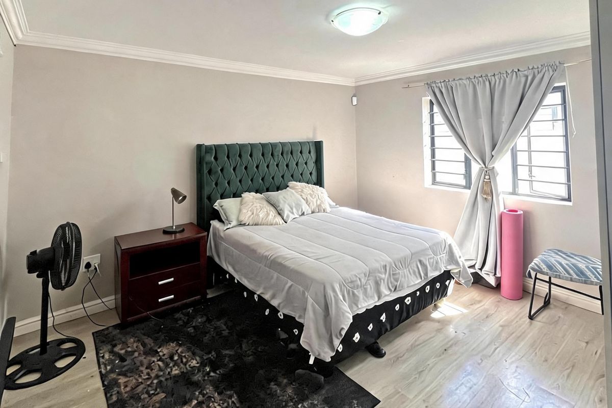 A bedroom featuring laminate flooring, security bars on the windows, and crown molding.