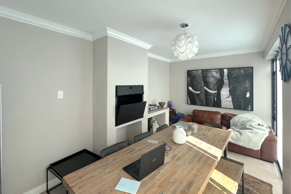 A living area featuring a built-in fireplace, crown molding, and tiled flooring, providing a comfortable and functional space.