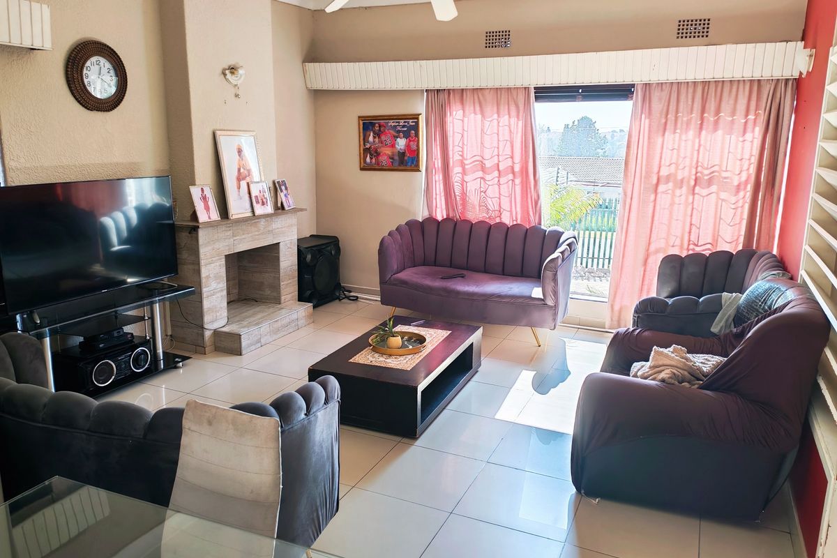 A living room featuring tiled flooring, a built-in fireplace, and a ceiling fan, with direct access to the outdoors via a sliding glass door.