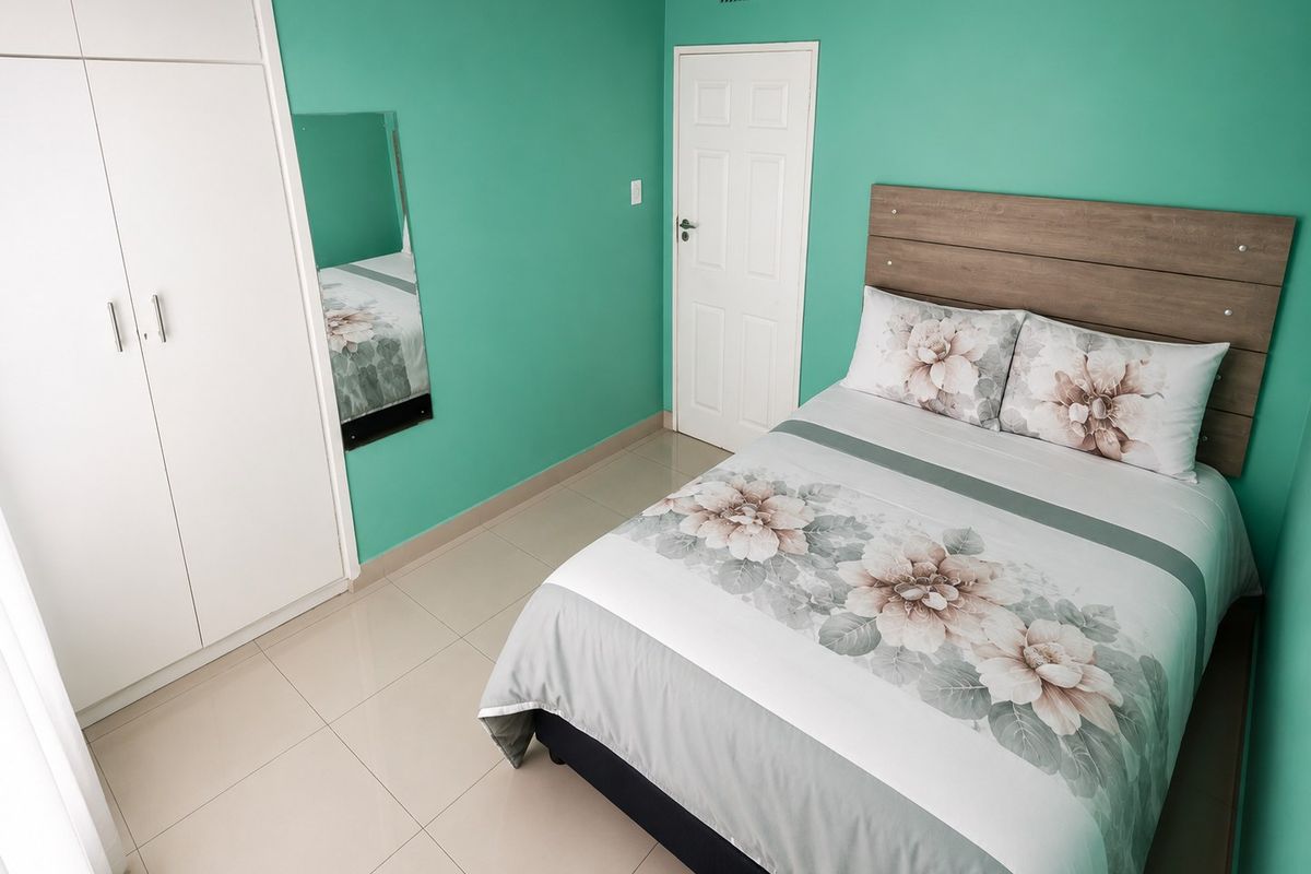 A well-maintained bedroom featuring tiled flooring, a built-in wardrobe, and a neutral panel door, finished with vibrant green wall paint.