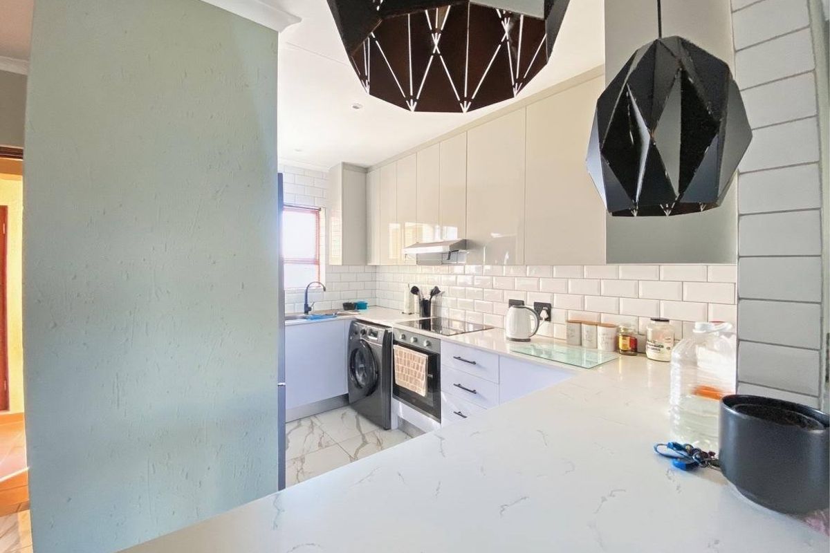 Modern kitchen featuring sleek high-gloss cabinetry, subway tile backsplash, stone countertops, and integrated appliances including an oven and hob.