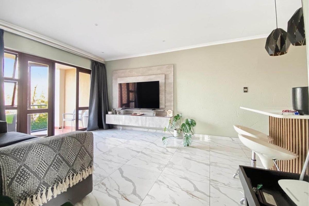 Modern living room featuring large-format marble-look floor tiles, a custom built-in media wall, and seamless access to a private balcony.