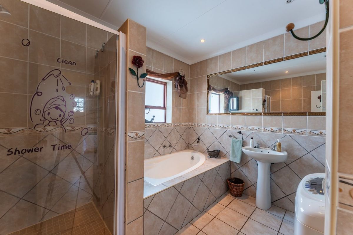 A functional bathroom featuring a built-in bathtub, a separate shower enclosure, and a pedestal sink with neutral wall and floor tiling.