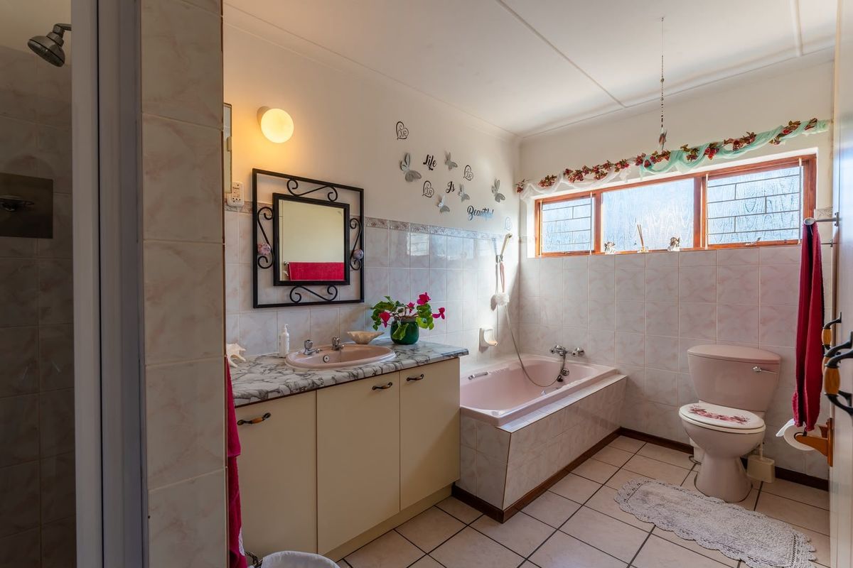 A functional bathroom featuring a built-in vanity, integrated sink, bathtub, and toilet with classic tiled finishes and natural light from a high window.