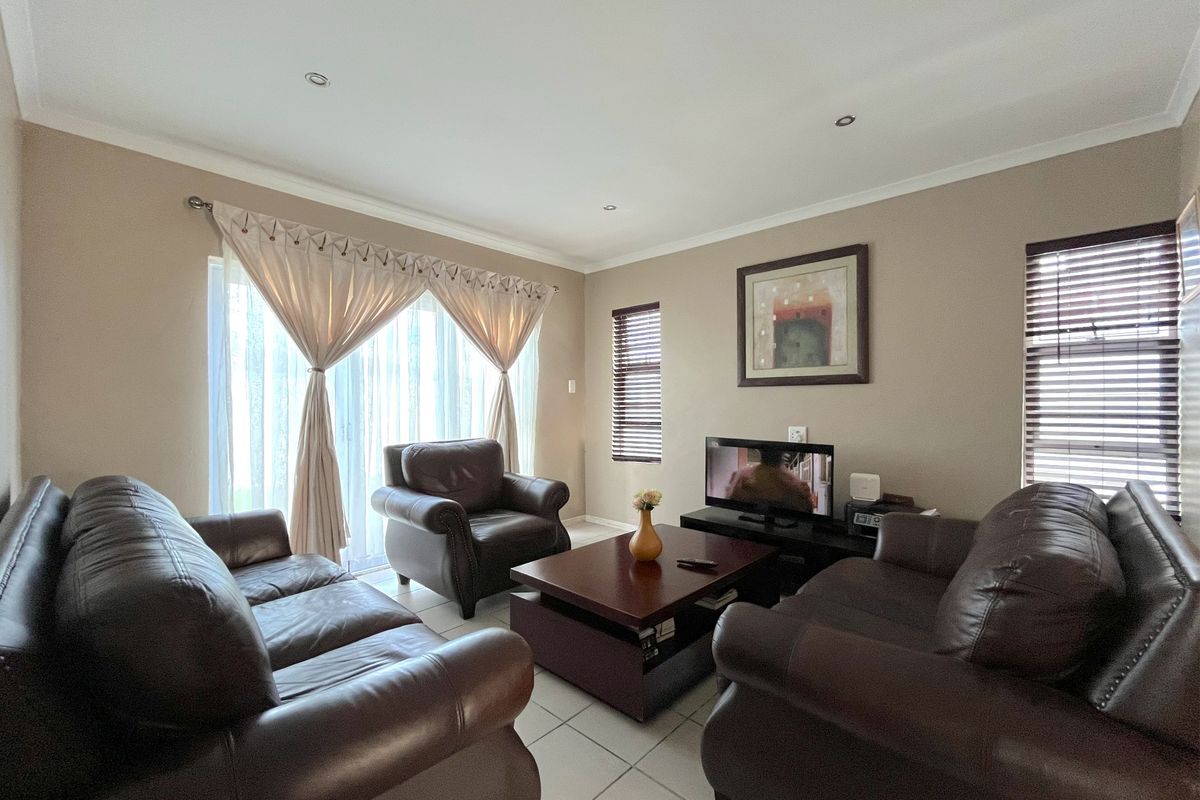 A comfortable living room featuring tiled flooring, recessed downlighting, and a large sliding glass door that provides natural light.