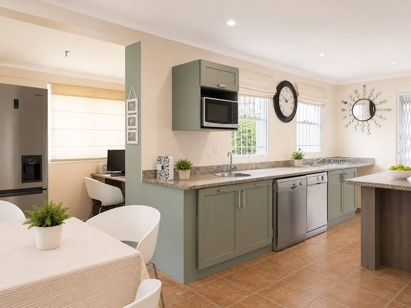 Modern kitchen featuring sage green cabinetry, granite countertops, integrated microwave, and a convenient built-in workspace, finished with durable tiled flooring.