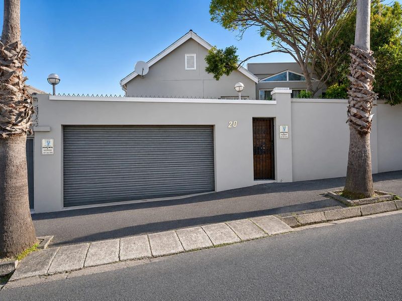 Front exterior view of the property featuring a secure boundary wall, roller garage door, and pedestrian access gate.
