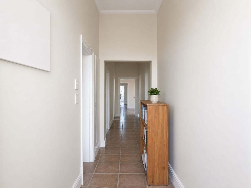 A bright and well-maintained hallway featuring neutral walls, tiled flooring, and classic architectural detailing, providing a clean transition between living spaces.