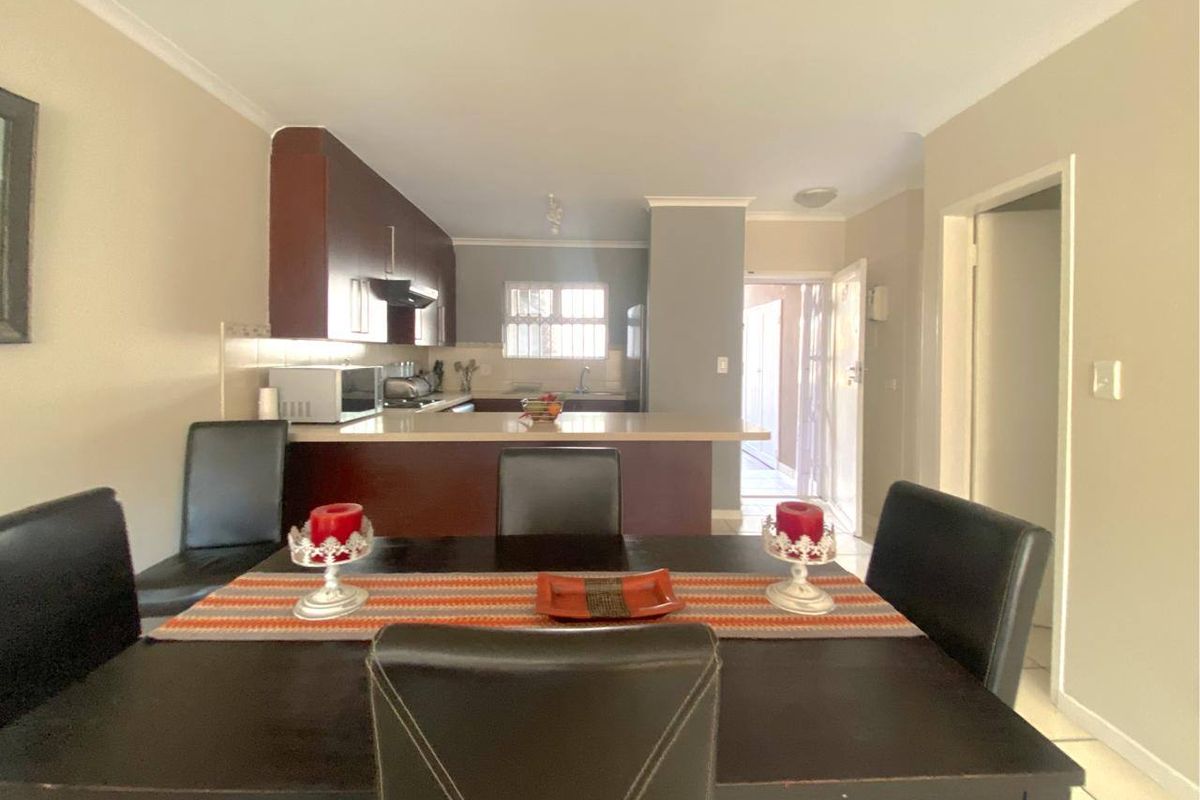 Open plan dining and kitchen area featuring dark wood cabinetry, a breakfast bar, and tiled flooring throughout.