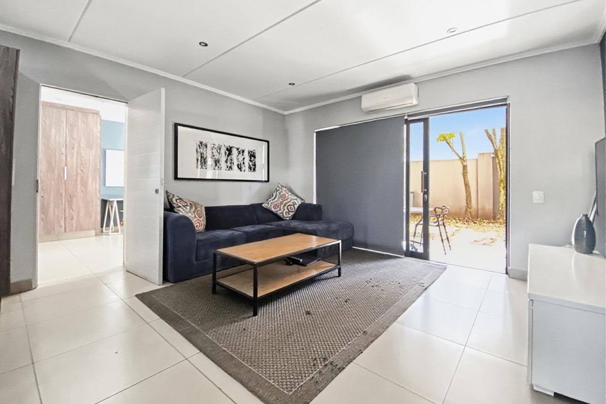 Bright living room featuring tiled flooring, recessed lighting, a wall-mounted air conditioner, and direct access to an outdoor patio area.