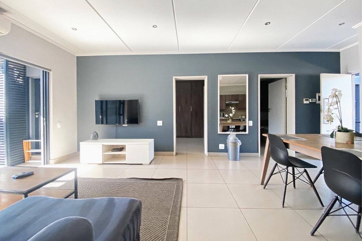 Spacious open-plan living and dining area featuring neutral tiled flooring, recessed ceiling lights, and direct access to an outdoor patio through sliding glass doors.