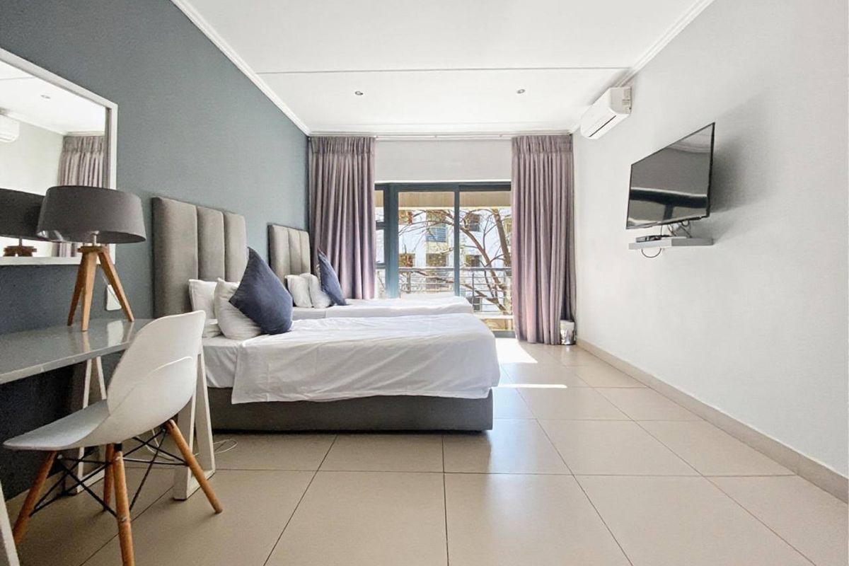 A well-maintained bedroom featuring tiled flooring, recessed lighting, an air conditioning unit, and a sliding glass door leading to an outdoor area.