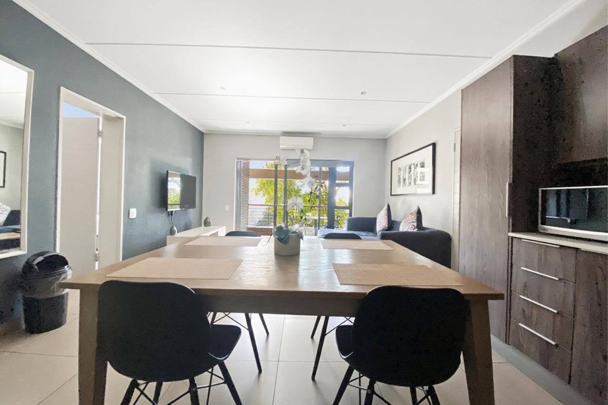 An open-plan living and dining area featuring tiled floors, modern cabinetry, and direct access to a balcony through sliding glass doors.