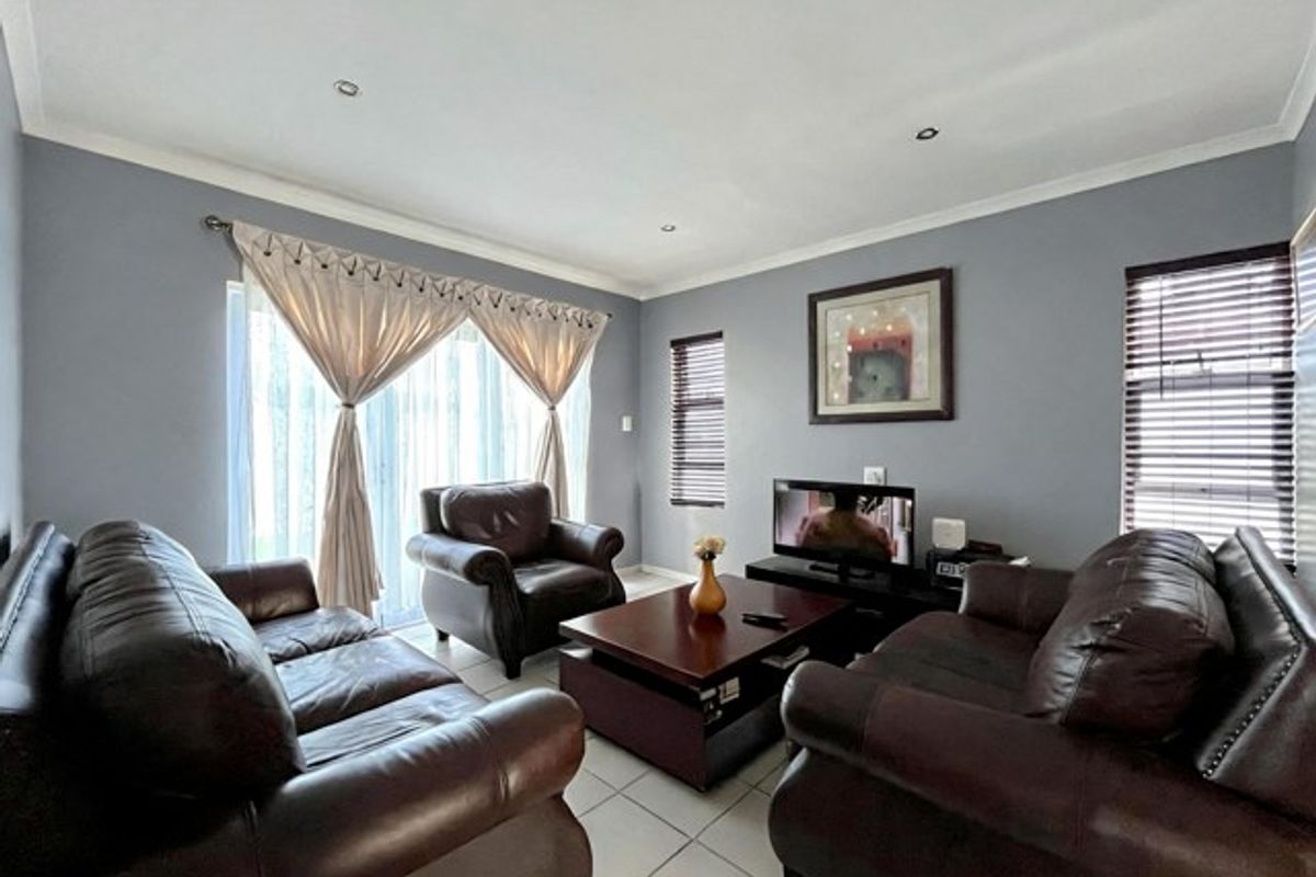 A well-maintained living room featuring tiled flooring, recessed downlights, and a sliding glass door with natural light access.