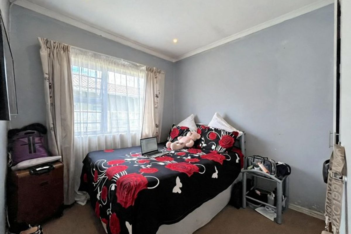 A standard bedroom featuring recessed downlights, coving, and a window with security bars, currently finished with neutral wall paint and carpet flooring.