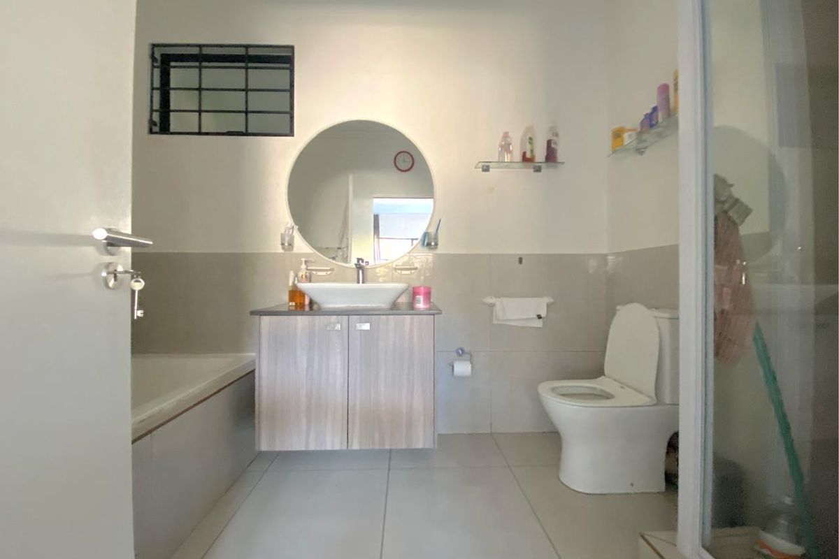 A functional bathroom featuring a vanity with a vessel sink, a bathtub, a separate shower enclosure, and neutral wall and floor tiling.