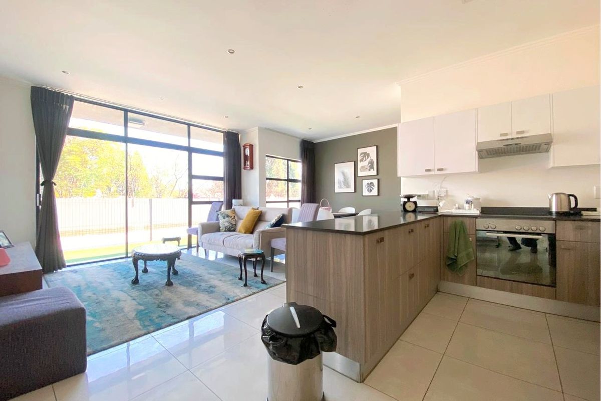Open-plan living area featuring a modern kitchen with built-in cabinetry, stone countertops, and large sliding glass doors leading to an outdoor space.