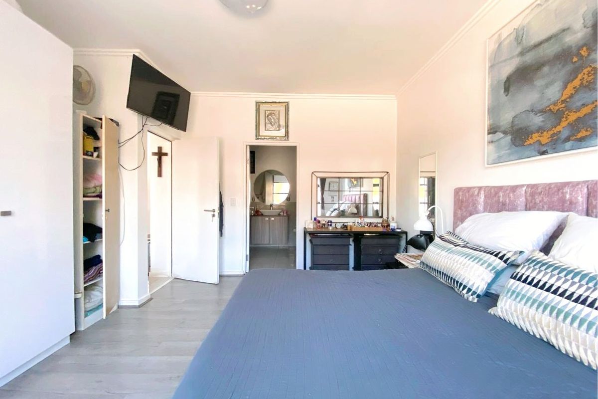 A bedroom featuring laminate flooring, a built-in wardrobe, and direct access to an en-suite bathroom.