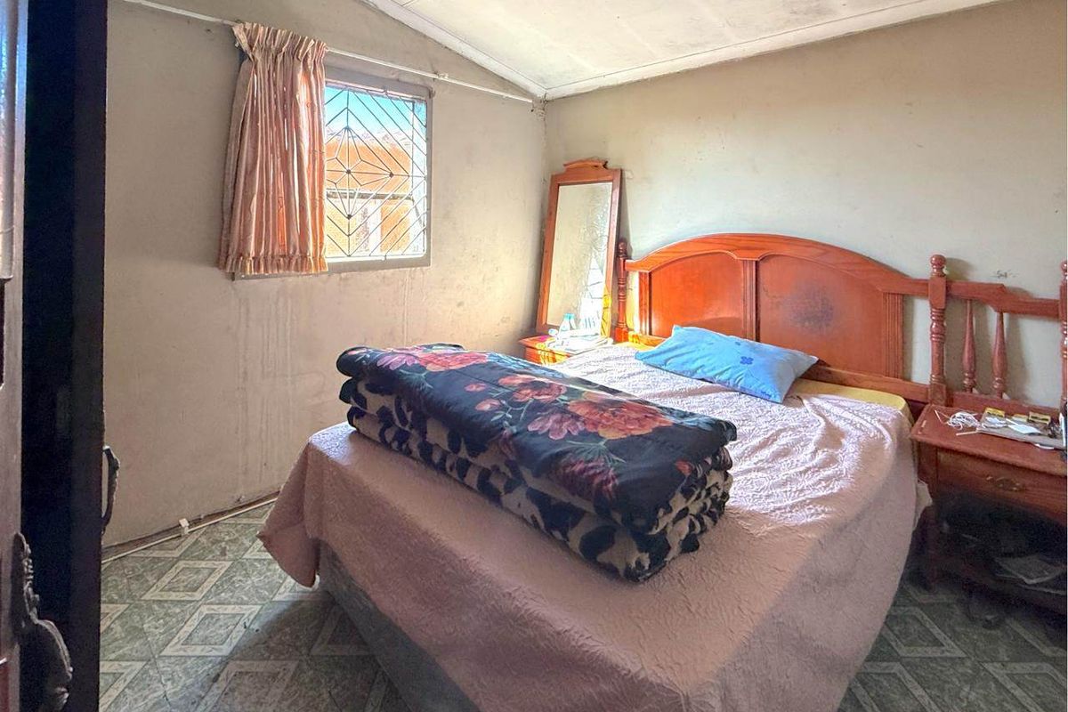 A bedroom featuring tiled flooring and a window with a security gate, requiring cosmetic updates to improve the overall condition of the space.