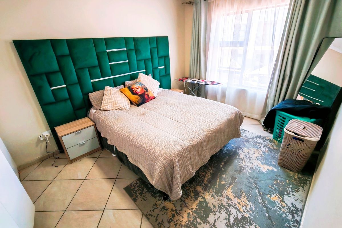A bedroom featuring tiled flooring and large windows with curtain rails, providing natural light.