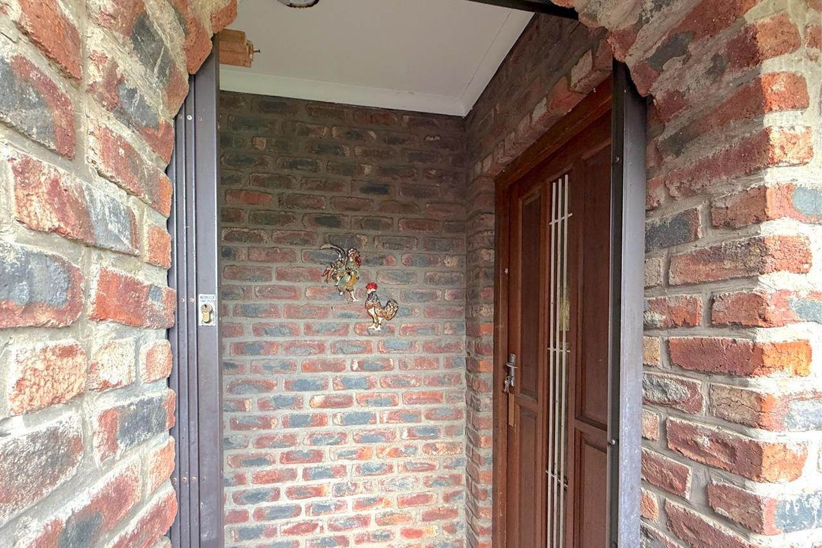 A covered entrance area featuring exposed brick walls and a traditional timber front door.