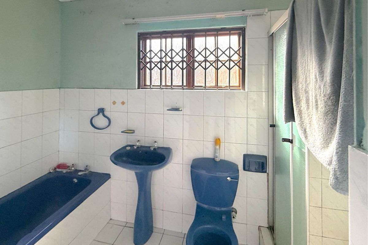 A dated bathroom featuring blue sanitaryware, a bathtub, a separate shower enclosure, and tiled wall finishes.