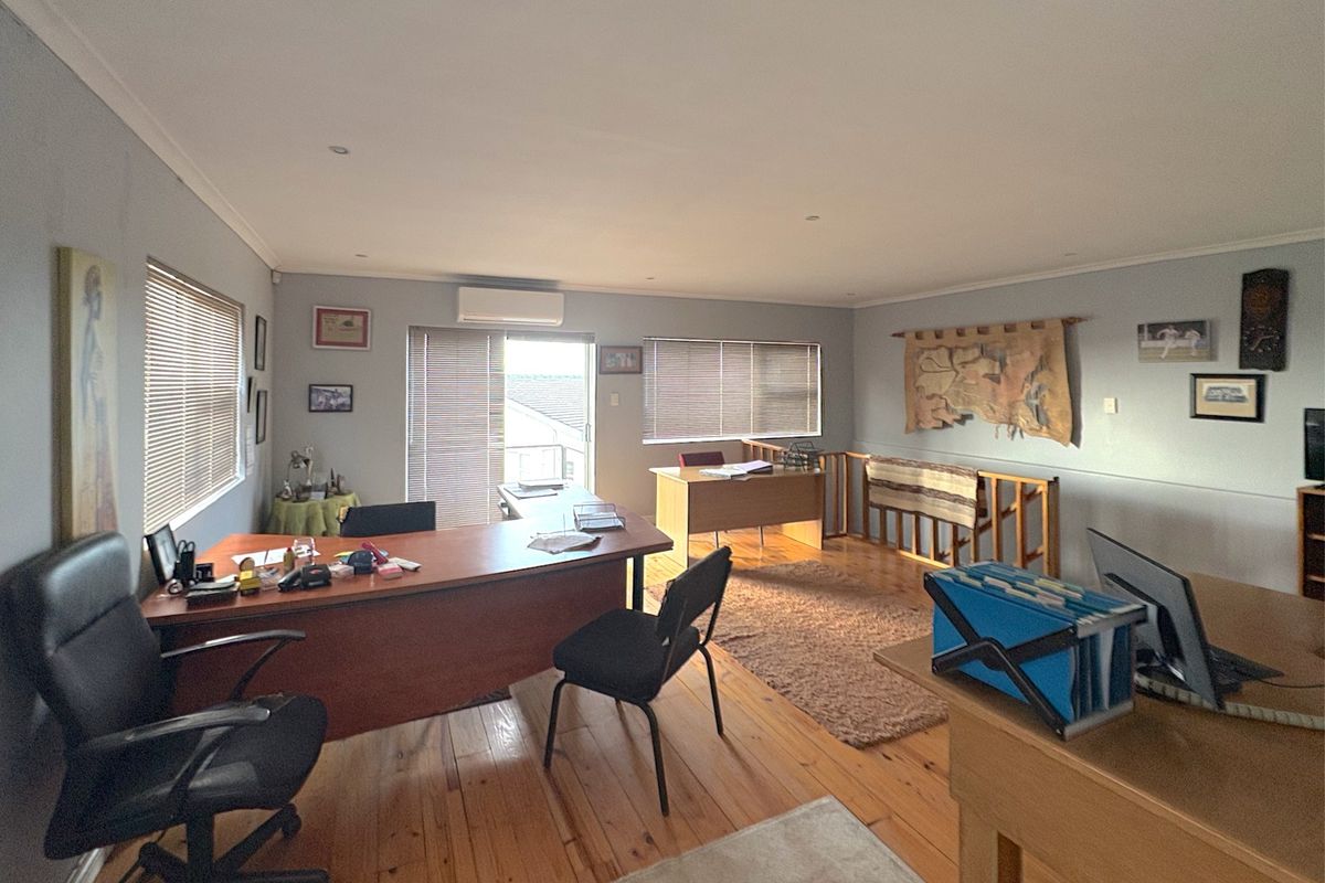 Spacious commercial office area featuring polished timber flooring, recessed lighting, and a split-system air conditioning unit with access to an outdoor balcony.