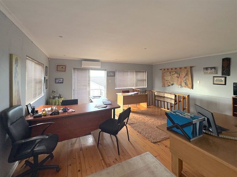 Spacious commercial office area featuring polished timber flooring, recessed lighting, and a split-system air conditioning unit with access to an outdoor balcony.
