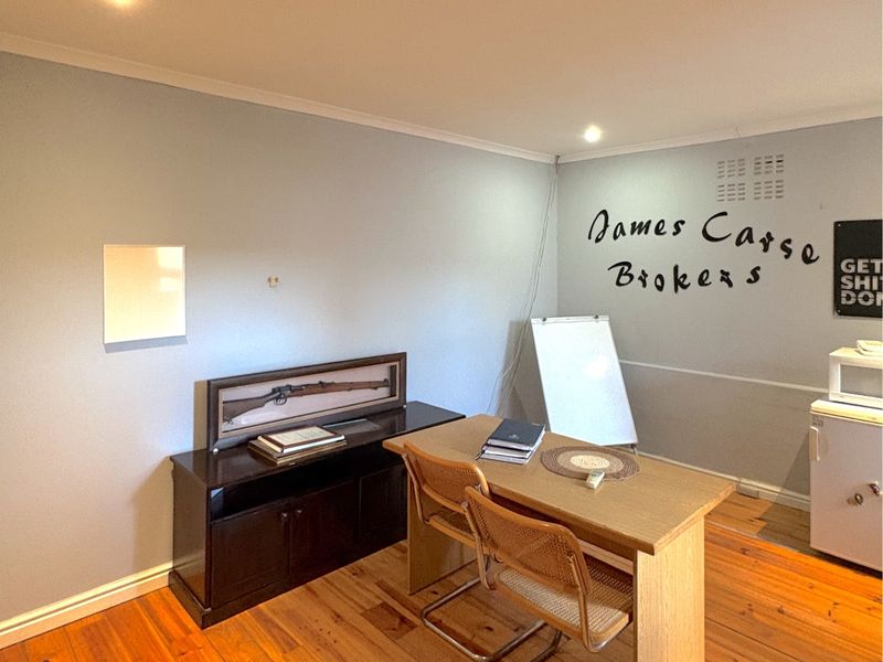 A functional office space featuring warm timber flooring, recessed downlighting, and neutral wall finishes, suitable for a professional commercial environment.