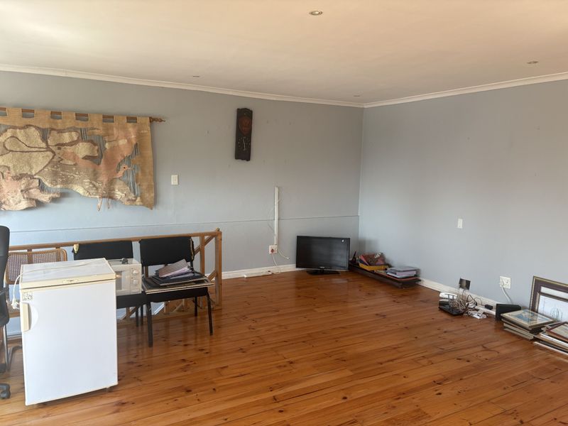 Spacious living area featuring polished timber flooring, recessed downlighting, and a timber balustrade, offering a versatile open-plan layout.