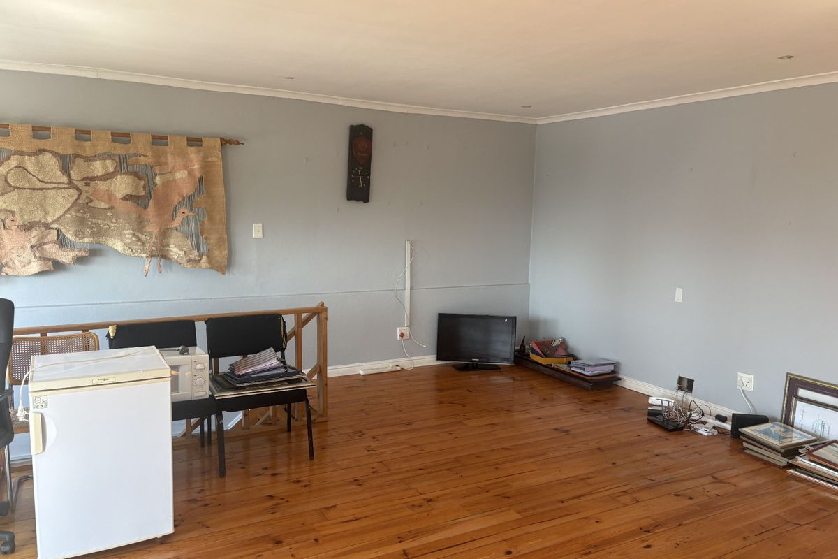 Spacious living area featuring polished timber flooring, recessed downlighting, and a timber balustrade, offering a versatile open-plan layout.