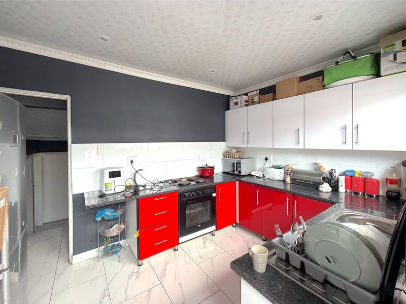 A functional kitchen featuring red and white cabinetry, granite countertops, a built-in oven, and tiled flooring with a modern marble-effect finish.