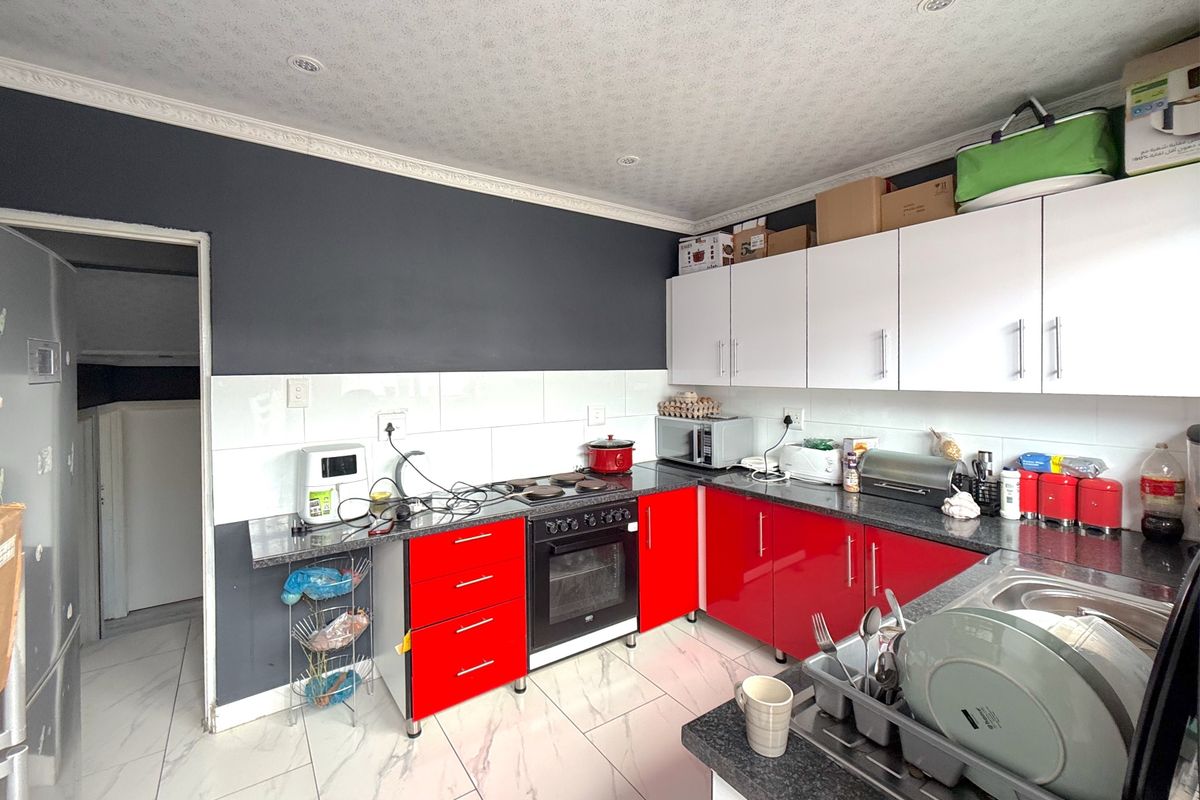 A functional kitchen featuring red and white cabinetry, granite countertops, a built-in oven, and tiled flooring with a modern marble-effect finish.
