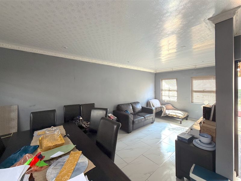 Open-plan living and dining area featuring large format floor tiles, decorative ceiling cornicing, and recessed lighting.