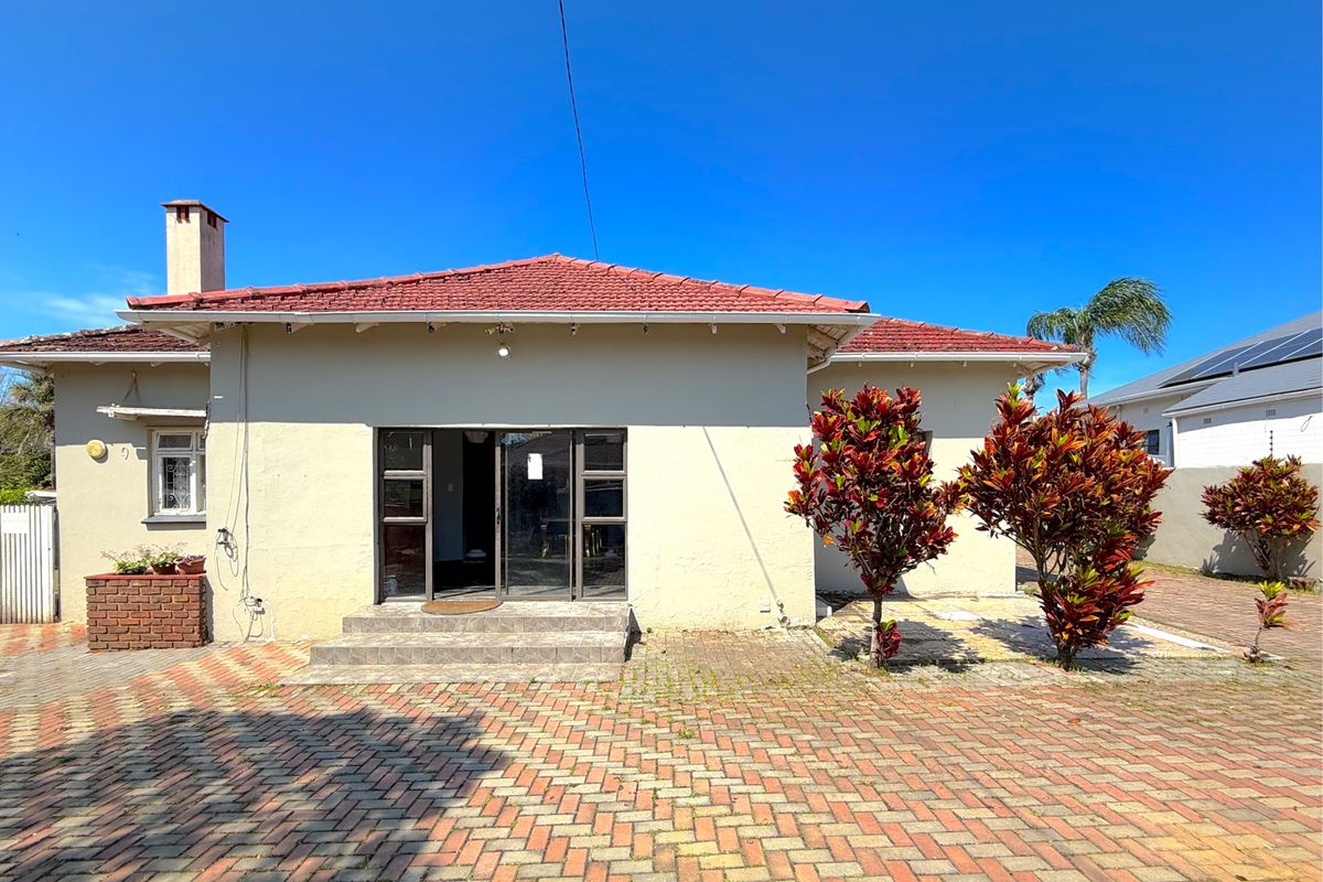Rear exterior view of the commercial property featuring a tiled roof, paved courtyard area, and sliding glass door access.