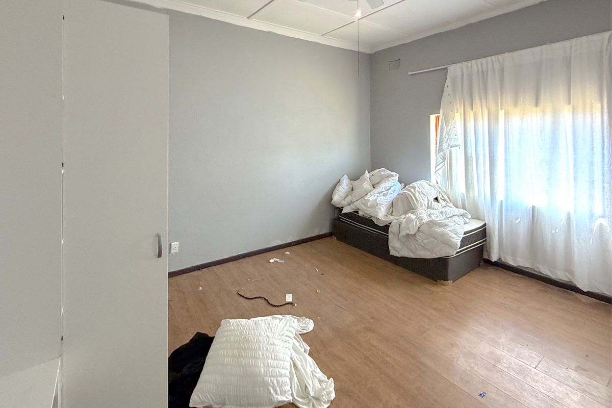 A bedroom featuring laminate flooring, a built-in wardrobe, and a ceiling fan, requiring cosmetic updates to improve its overall condition.