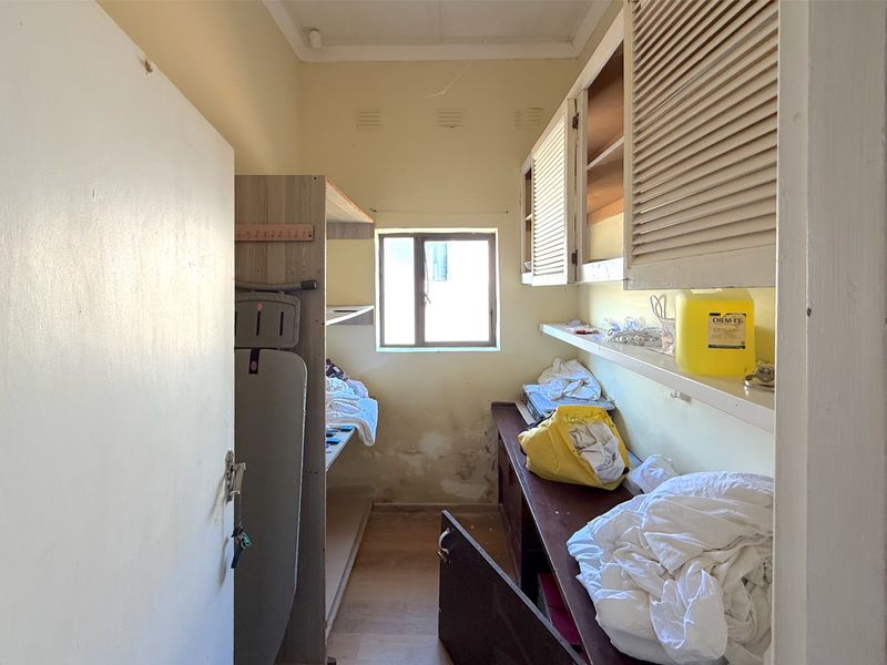 A small utility or laundry room featuring built-in cabinetry and shelving, currently showing signs of wear and requiring maintenance or renovation.