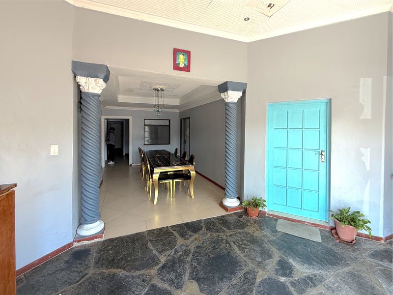Interior living area featuring decorative columns, mixed stone and tile flooring, and a recessed ceiling with integrated lighting.