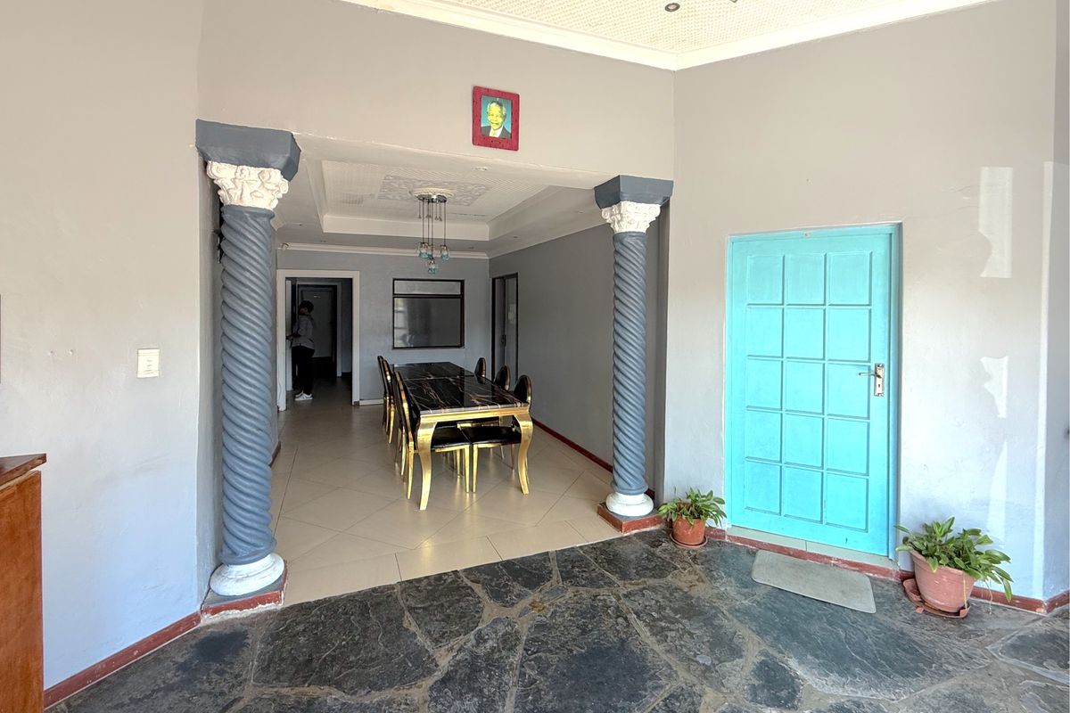 Interior living area featuring decorative columns, mixed stone and tile flooring, and a recessed ceiling with integrated lighting.