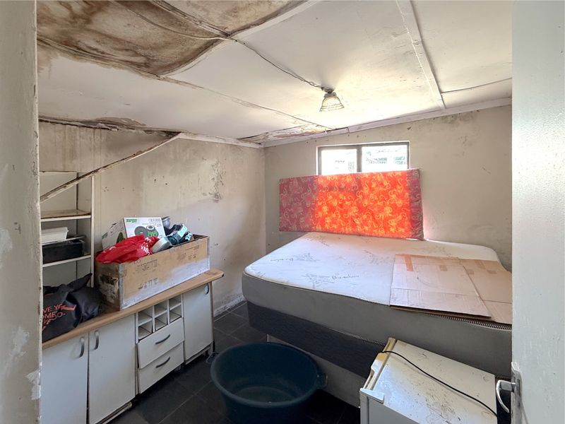 A bedroom space requiring significant renovation, featuring built-in cabinetry and tiled flooring, with visible signs of severe ceiling and wall water damage.