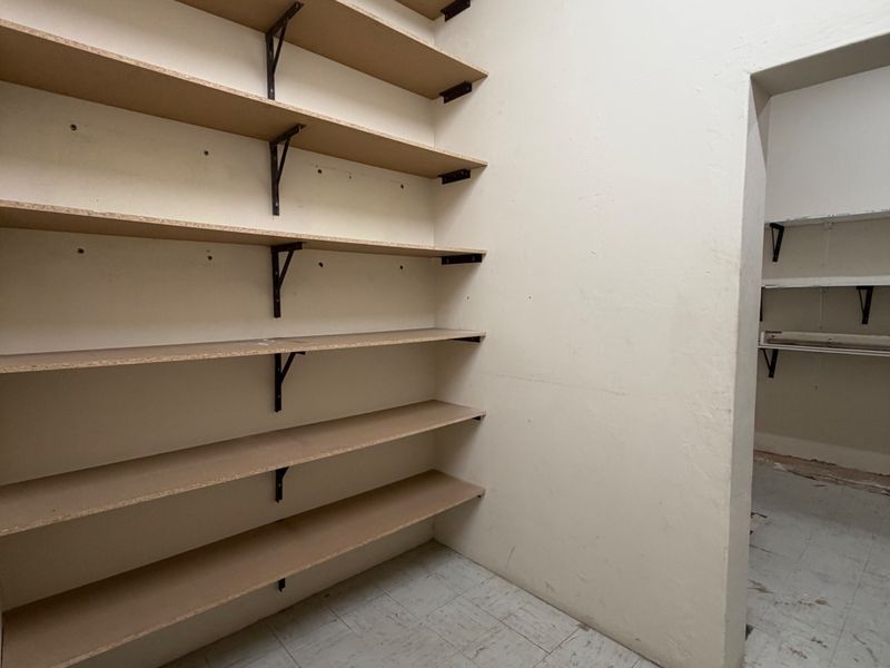 A functional utility or storage room featuring extensive built-in wall shelving and durable vinyl tile flooring, suitable for industrial or commercial storage needs.