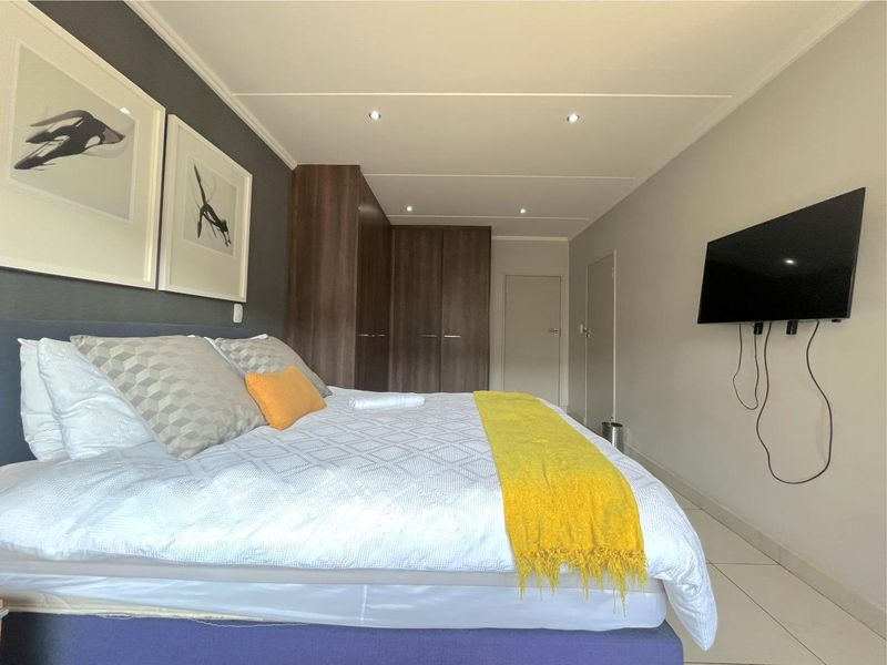 A well-maintained bedroom featuring built-in cupboards, tiled flooring, and recessed downlighting.
