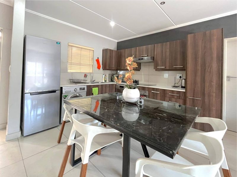 Modern kitchen featuring dark wood cabinetry, light countertops, integrated appliances, and tiled flooring, offering a functional and contemporary cooking space.