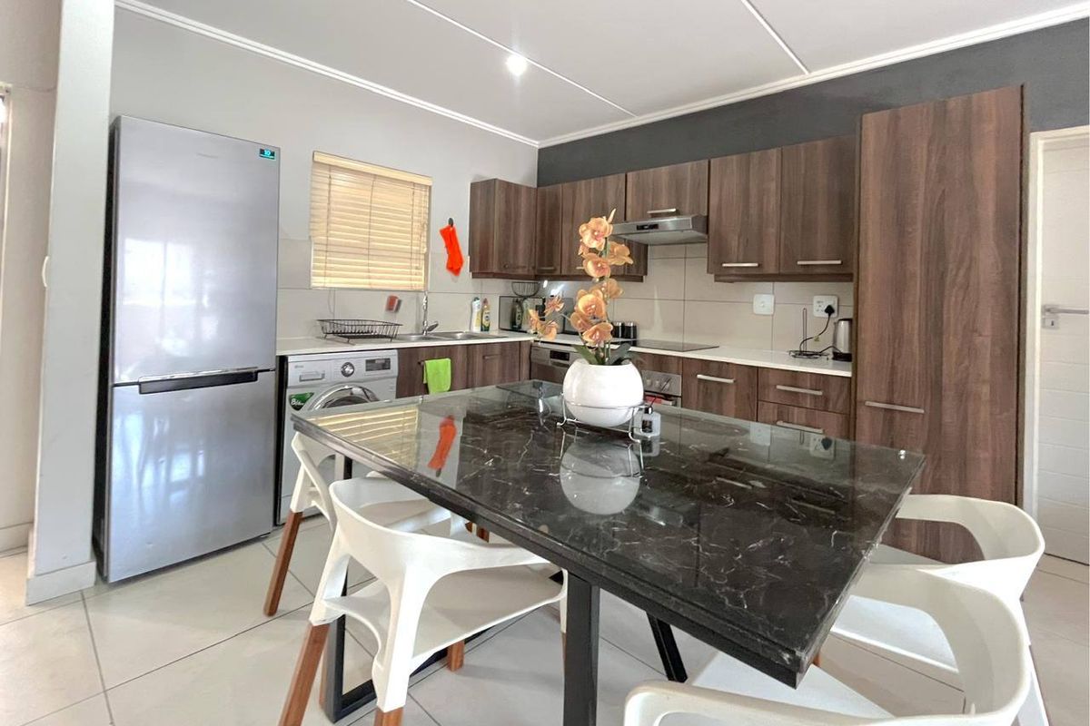 Modern kitchen featuring dark wood cabinetry, light countertops, integrated appliances, and tiled flooring, offering a functional and contemporary cooking space.