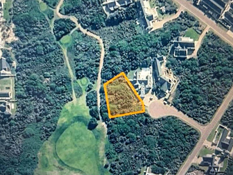 An aerial view of a vacant residential land plot highlighted in orange, situated within a landscaped estate environment.