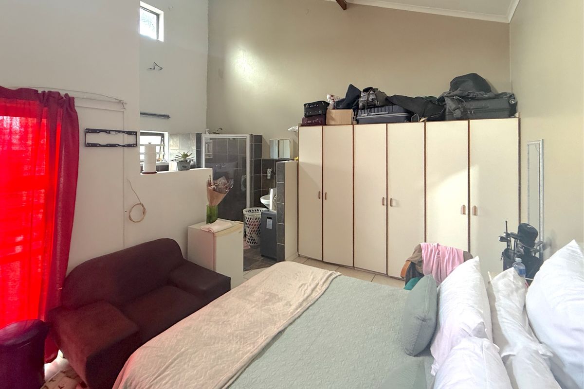 Spacious bedroom featuring vaulted ceilings, built-in cupboards, and an integrated en-suite shower area with tiled flooring.
